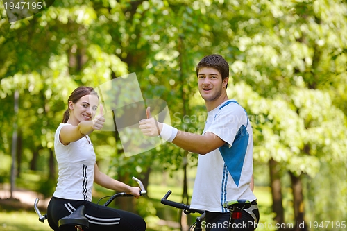 Image of Happy couple riding bicycle outdoors