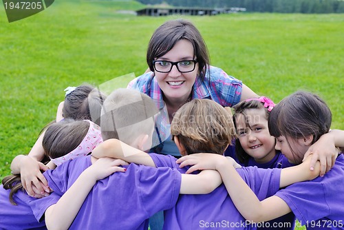 Image of happy kids group with teacher in nature