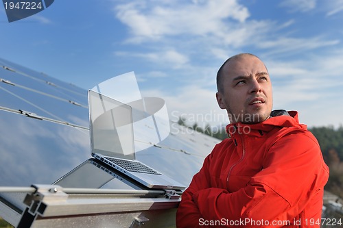 Image of engineer using laptop at solar panels plant field