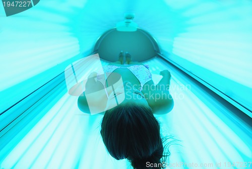 Image of Beautiful young woman tanning in solarium