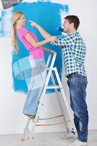 Image of happy couple paint wall at new home