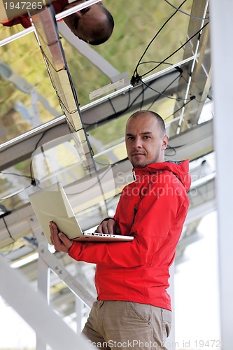 Image of engineer using laptop at solar panels plant field