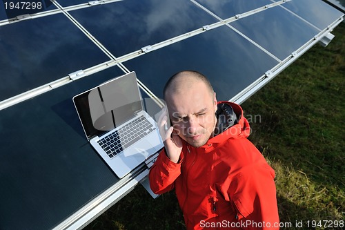 Image of engineer using laptop at solar panels plant field