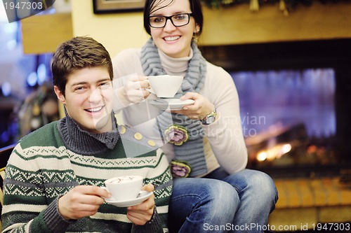 Image of Young romantic couple sitting and relaxing in front of fireplace