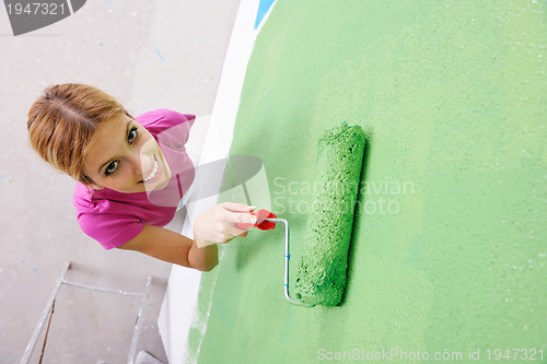 Image of happy smiling woman painting interior of house