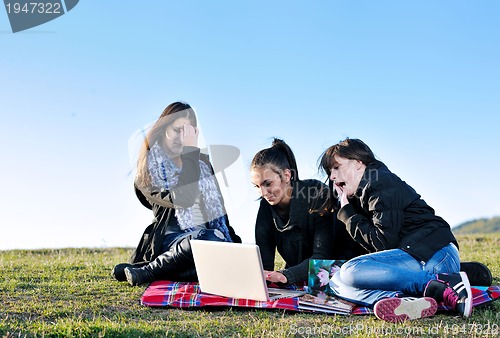 Image of group of teens working on laptop outdoor