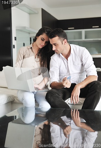 Image of joyful couple relax and work on laptop computer at modern home