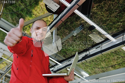 Image of engineer using laptop at solar panels plant field