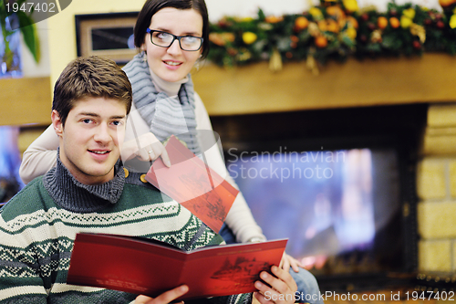 Image of Young romantic couple relax on sofa in front of fireplace at hom