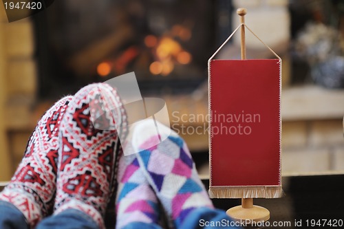 Image of Young romantic couple sitting and relaxing in front of fireplace