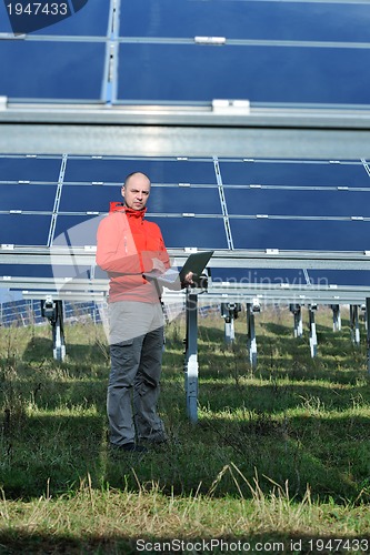 Image of engineer using laptop at solar panels plant field