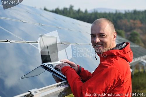 Image of engineer using laptop at solar panels plant field