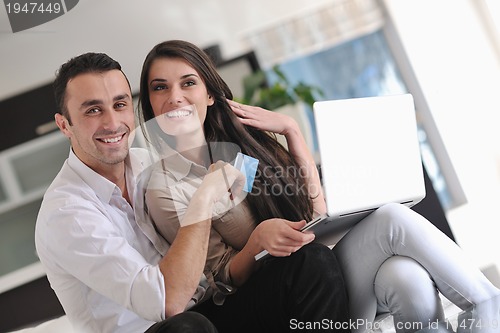 Image of joyful couple relax and work on laptop computer at modern home