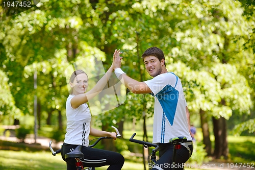 Image of Happy couple riding bicycle outdoors