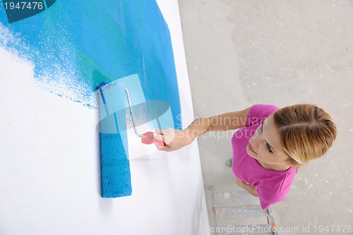 Image of happy smiling woman painting interior of house