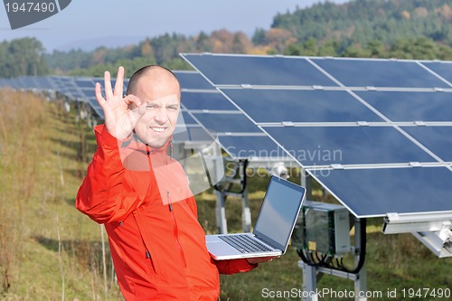 Image of engineer using laptop at solar panels plant field