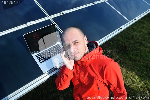 Image of engineer using laptop at solar panels plant field