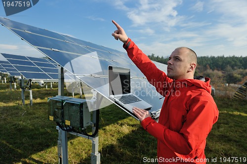 Image of engineer using laptop at solar panels plant field