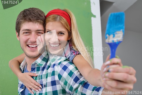 Image of happy couple paint wall at new home