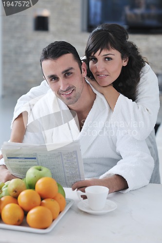 Image of Happy couple reading the newspaper in the kitchen at breakfast