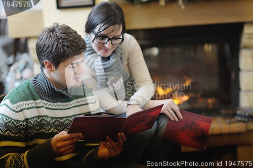 Image of Young romantic couple sitting and relaxing in front of fireplace