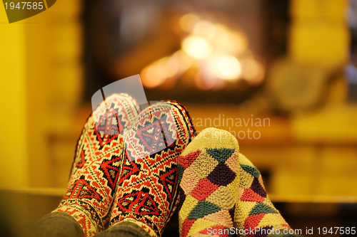 Image of Young romantic couple sitting on sofa in front of fireplace at h