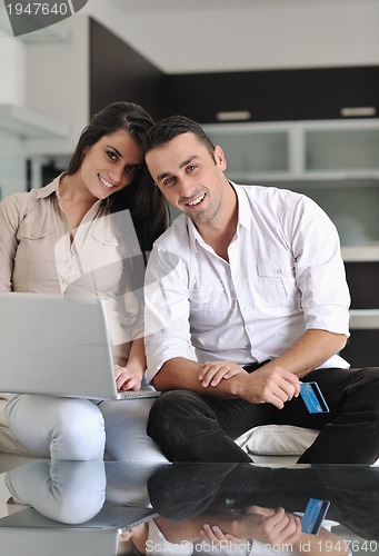 Image of joyful couple relax and work on laptop computer at modern home