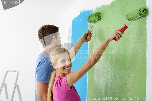 Image of happy couple paint wall at new home