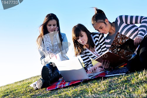 Image of group of teens working on laptop outdoor