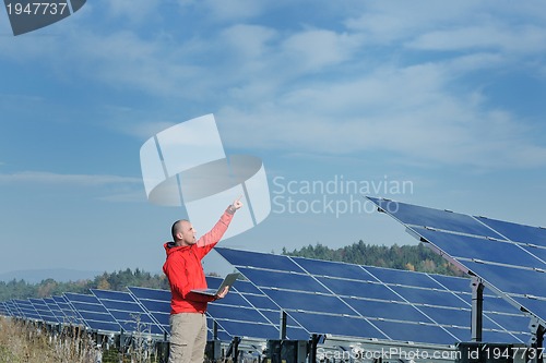 Image of engineer using laptop at solar panels plant field