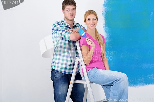 Image of happy couple paint wall at new home