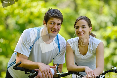 Image of Happy couple riding bicycle outdoors