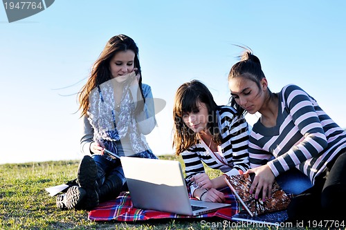 Image of group of teens working on laptop outdoor
