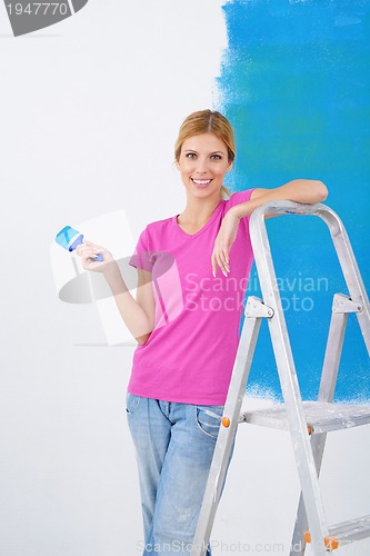 Image of happy smiling woman painting interior of house