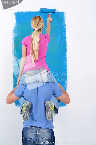 Image of happy couple paint wall at new home