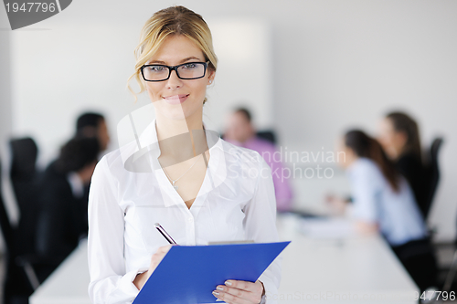 Image of business woman standing with her staff in background
