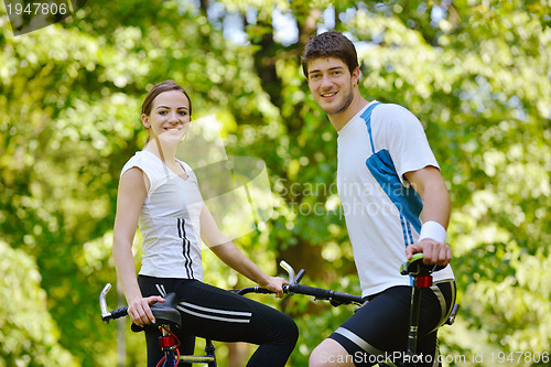 Image of Happy couple riding bicycle outdoors