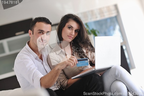 Image of joyful couple relax and work on laptop computer at modern home