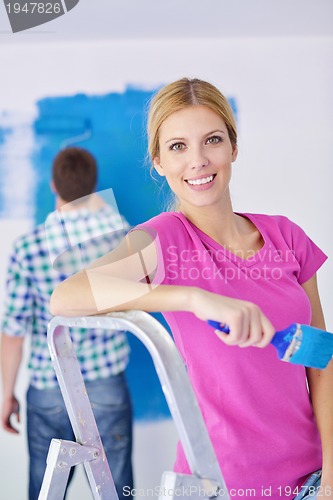 Image of happy couple paint wall at new home