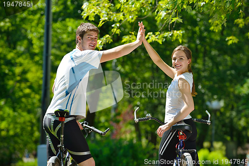 Image of Happy couple riding bicycle outdoors