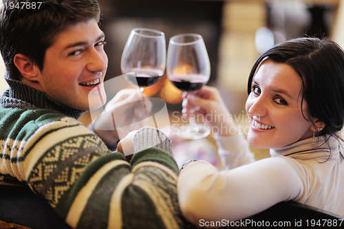 Image of Young romantic couple sitting on sofa in front of fireplace at h