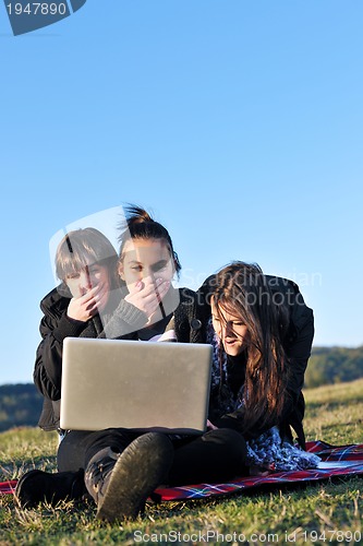 Image of group of teens working on laptop outdoor