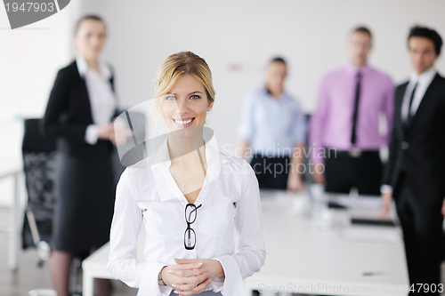 Image of business woman standing with her staff in background