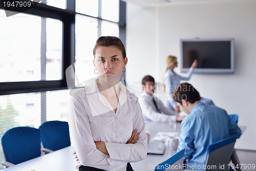 Image of business woman with her staff in background at office