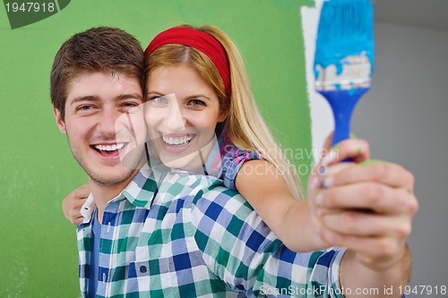 Image of happy couple paint wall at new home