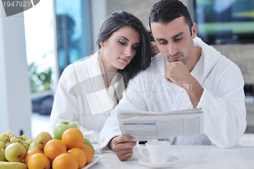 Image of Happy couple reading the newspaper in the kitchen at breakfast