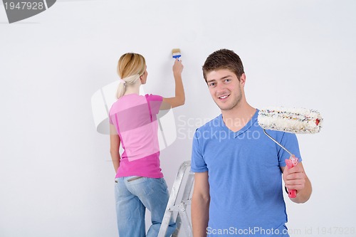 Image of happy couple paint wall at new home