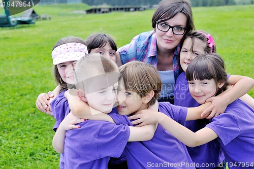 Image of happy kids group with teacher in nature