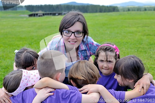 Image of happy kids group with teacher in nature