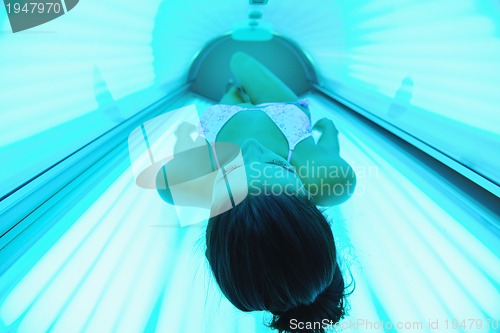 Image of Beautiful young woman tanning in solarium